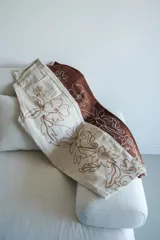 Pantalón slouchy tiro medio color beige con bordado floral marrón.