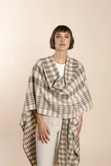 Ruana marrón con diseño a cuadros blancos, terminación envivada y flecos cortos.