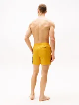 Short de baño amarillo con cintura elástica ajustable con cordón. Presenta una banda vertical en el lateral con los colores blanco, azul marino y rojo.