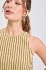 Vestido midi sin mangas, de corte recto y holgado, con cuello redondo. Presenta un estampado de rayas verticales finas en tonos amarillo claro y verde oliva/marrón.