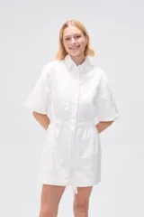 Mono corto blanco de algodón, con cuello camisero, cierre frontal con botones, mangas cortas y bolsillos.