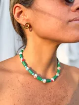 Collar corto de cuentas, compuesto por cuentas cilíndricas verdes, cuentas redondas con estampado floral en tonos pastel (rosa, celeste, blanco) y cuentas redondas pequeñas de color celeste.