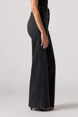 Pantalón de jean acampanado negro de tiro alto con dos botones a la vista.