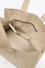 Bolso shopper color beige con diseño trenzado y doble asa de hombro. Cuenta con un bolsillo interior con cierre de cremallera y cierre principal con clip.