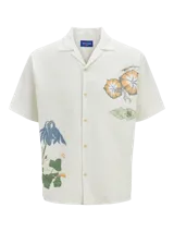 Camisa de algodón color crudo con estampado de flores y billetes, cuello resort, calce relajado, mangas cortas y cierre de botones.