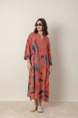 Vestido largo de lino color verde militar con estampado de hojas en tonos azul, naranja y marrón. Tiene cuello mao con botones, mangas tres cuartos y un bolsillo en el pecho.