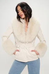 Blazer color crema con cuello y puños de piel sintética color crema. Tiene corte entallado, cierre frontal con botones y cinturón con hebilla.