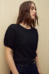 Top negro de tejido texturizado con mangas cortas abullonadas y cuello redondo.