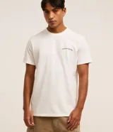 Remera de algodón color crudo, de corte recto y manga corta. Presenta un pequeño estampado con texto "Hawaiian Islands" en el pecho.