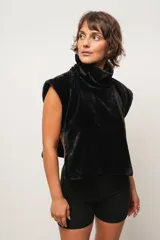 Chaleco de peluche negro con cuello alto y tiras laterales, de corte suelto.