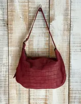 Bolso de hombro color blanco con textura craquelada, correa regulable con hebilla, interior forrado y cierre superior. Incluye llavero y bolsillos internos.