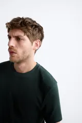 Jersey de punto color marrón oscuro, de corte relajado (relaxed fit), con cuello redondo y manga corta.