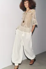 Top de crochet color crema, con cuello redondo y mangas cortas.
