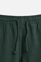 Pantalón largo verde oscuro de algodón con textura, corte recto y cintura elástica ajustable con cordón.