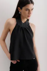 Top negro sin mangas con cuello halter con volados y espalda descubierta.