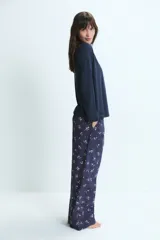 Pijama de dos piezas confeccionado en mezcla de bambú y algodón. Incluye una remera de manga larga lisa en color azul marino con un pequeño detalle bordado de corazones en el pecho y un pantalón largo con estampado floral y cintura elástica.