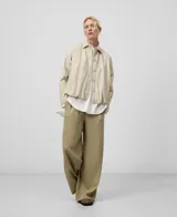 Bomber color beige de piel sintética con cuello solapa, manga larga redondeada con pinza en el codo, cierre frontal con botones y bolsillos laterales.