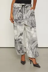 Pantalón amplio con estampado abstracto en blanco y negro, cintura elástica ajustable con cordón y tobillos fruncidos.