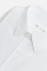 Camisa celeste de algodón, corte regular fit, con cuello italiano, manga larga con puños abotonados y cierre frontal con botones.