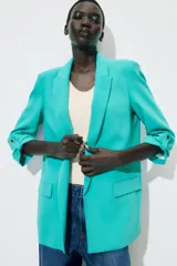 Blazer marrón con cuello solapa y hombreras. Manga tres cuartos con trabilla y botón dorado. Bolsillos delanteros con solapa.