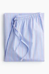 Pantalón de pijama largo de algodón con estampado de rayas verticales celestes y rojas. Tiene cintura elástica con cordón ajustable y corte holgado.