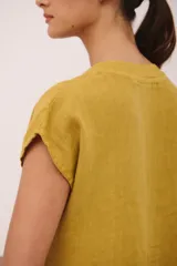 Vestido corto de lino color vino tinto, con escote en V y mangas cortas tipo musculosa. Presenta un corte holgado con volados en el ruedo.