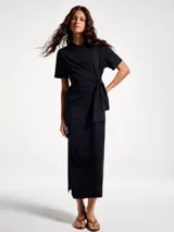 Vestido largo negro de manga corta, con cuello redondo y detalle de nudo o lazo ajustable en la cintura.