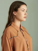 Camisa celeste de algodón con corte clásico y caída suelta. Presenta vivos en cuadrillé trazados en puños, canesú de la espalda y al pie del cuello.