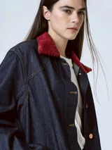 Chaqueta de denim azul oscuro con cuello de piel sintética color borgoña, cierre frontal con botones a presión, bolsillos de parche con solapa en el pecho y bolsillos laterales.
