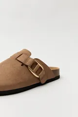 Zuecos negros con base de corcho, puntera cerrada y hebilla dorada decorativa.