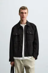 Sobrecamisa color beige de tejido efecto ante, corte regular fit, con cuello solapa, manga larga con puños abotonados, bolsillos de parche con solapa en el pecho y bolsillos de ojal en la cadera.