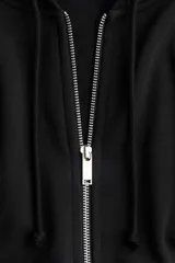 Campera con capucha negra en felpa con interior cepillado suave. Modelo con hombros caídos, capucha forrada en punto con cordón para ajustar, cierre y bolsillo canguro. Puños y bajo en punto elástico acanalado.