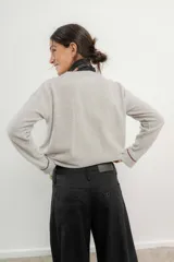 Sweater de punto gris con cuello en V y ribetes en contraste.