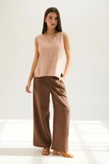 Pantalón de lino azul de corte palazzo con botón decorativo en la cintura.