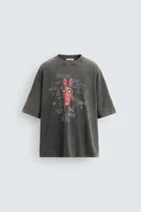 Camiseta gris con efecto lavado, cuello redondo y manga corta. Estampado frontal con conejo, texto y efecto de pintura.