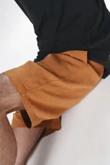 Bermuda color ocre de algodón con elástico en la cintura, cordón de ajuste con ojalillos y dos bolsillos delanteros.