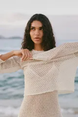 Top color crudo de tejido crochet calado, con cuello redondo y mangas largas.
