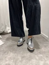Zapatos de cuero plateado con diseño clásico y cordones, ideales para combinar con diferentes estilos.