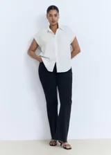 Camisa blanca sin mangas con cuello camisero y cierre frontal con botones.