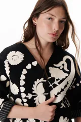 Chaqueta negra con bordados florales en color crudo, cuello en V y mangas 3/4 con puños a rayas.