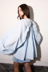 Camisa celeste super holgada con hombro caído y manga ancha. Tiene un volado en el cuello y efecto arrugado en la espalda.