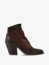 Bota corta de gamuza color marrón oscuro, con puntera cuadrada y cierre de cremallera en la parte trasera. Posee un taco ancho y alto de madera oscura.