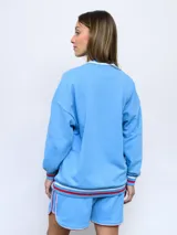 Buzo de felpa azul marino con mangas raglán rojas y detalles tricolor en puños, mangas y cuello. Incluye logo de Umbro bordado en el pecho y escudo del Club Nacional de Football.