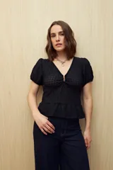 Top blanco con textura tramada, escote en V con leve frunce central, mangas cortas con elástico y volado sutil en el ruedo. Tejido con elasticidad.