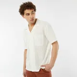 Camisa de manga corta color blanco hueso, de tejido calado con cuello solapa y bolsillo de parche en el pecho.