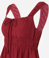 Blusa texturizada color borgoña, con breteles anchos, escote cuadrado, lazo en el busto y volado en el ruedo.