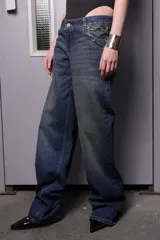 Pantalón de jean azul oscuro de corte ancho con cadena decorativa en la cintura.