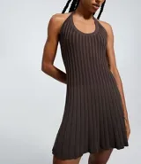 Vestido sin mangas de corte evasé, color verde oliva, con escote redondo y detalle de lazo en el cuello. El tejido presenta un efecto tricot texturizado acanalado.