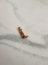 Dije de acero quirúrgico hipoalergénico con forma de bota texana dorada con detalles grabados en rojo.