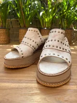 Sandalias de cuero color blanco con plataforma de madera y goma, taco de 7cm y tachas color cobre. Hechas a mano en Uruguay.